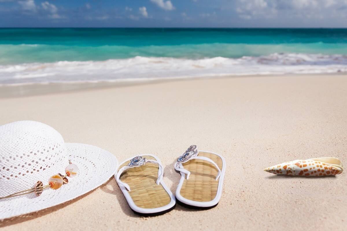 Spiaggia caraibica con cappello e infradito